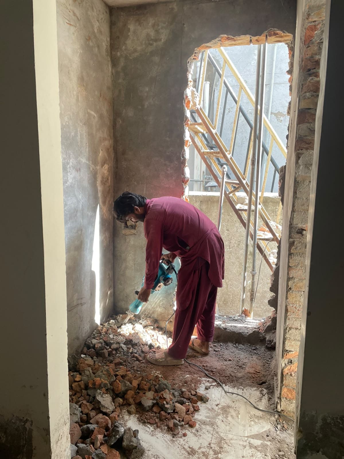 A worker breaking out a new doorway beside the staircase