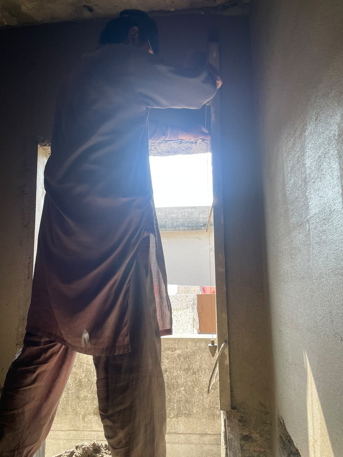 A worker shaping the edge of a new window opening against the light