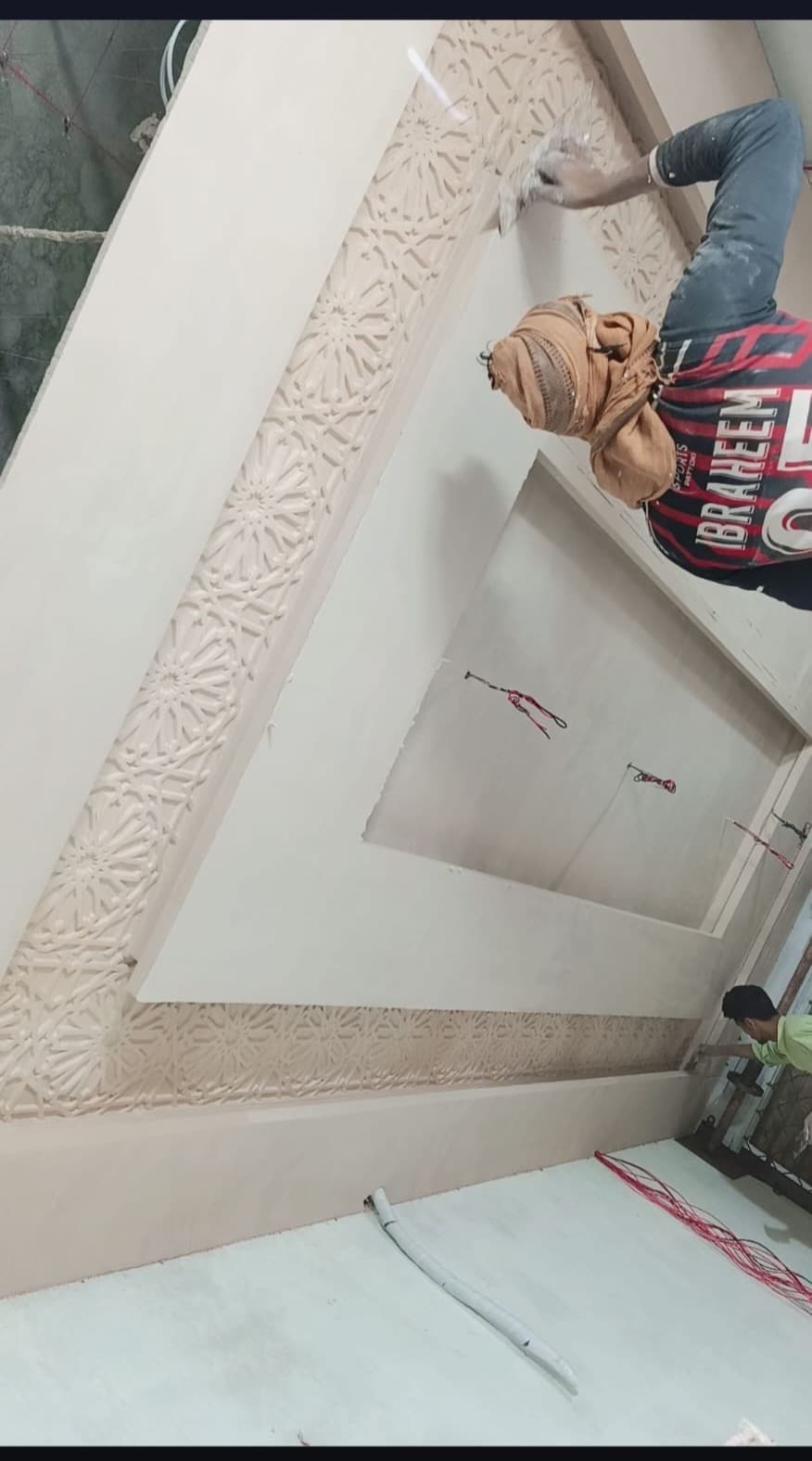 A worker finishing the carved border around a recessed ceiling panel
