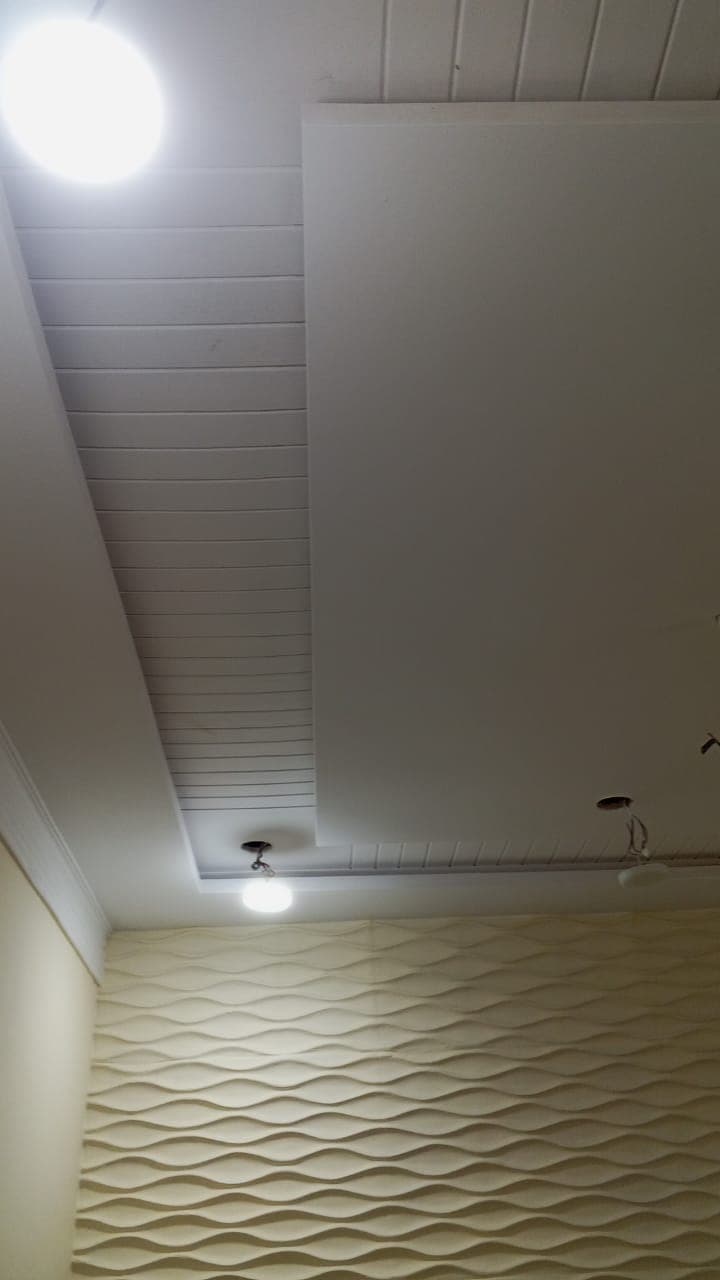 A panelled false ceiling over a wall finished in wave-pattern panels