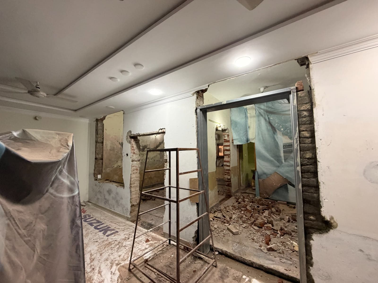 A wall opened up in a hall, with rubble and scaffolding inside the new opening