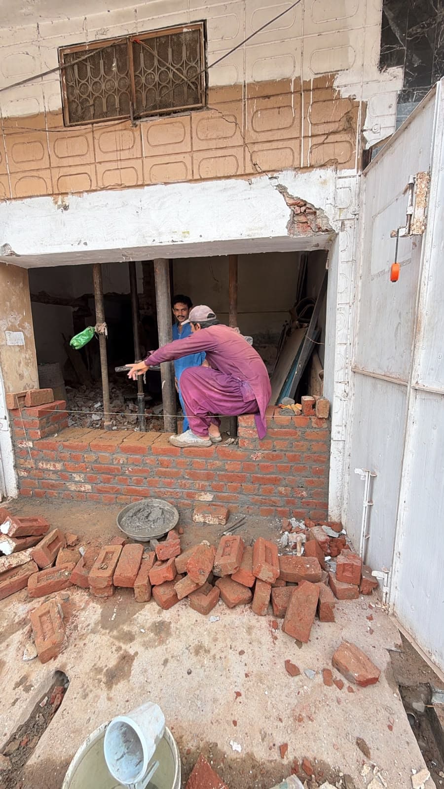 A worker building a new brick wall across an opening