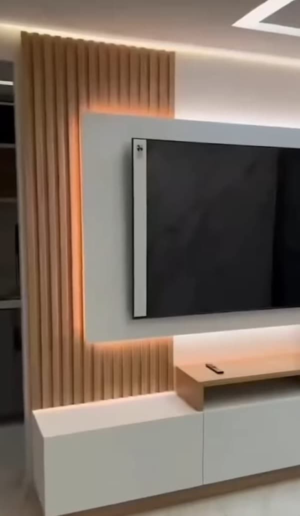 A white TV panel with a warm LED glow, set against wooden fluted panels above a white console