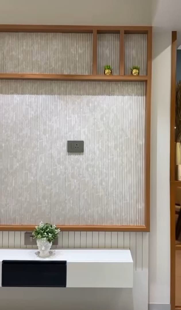 A textured feature wall framed in wood, with open shelves above and a white floating console