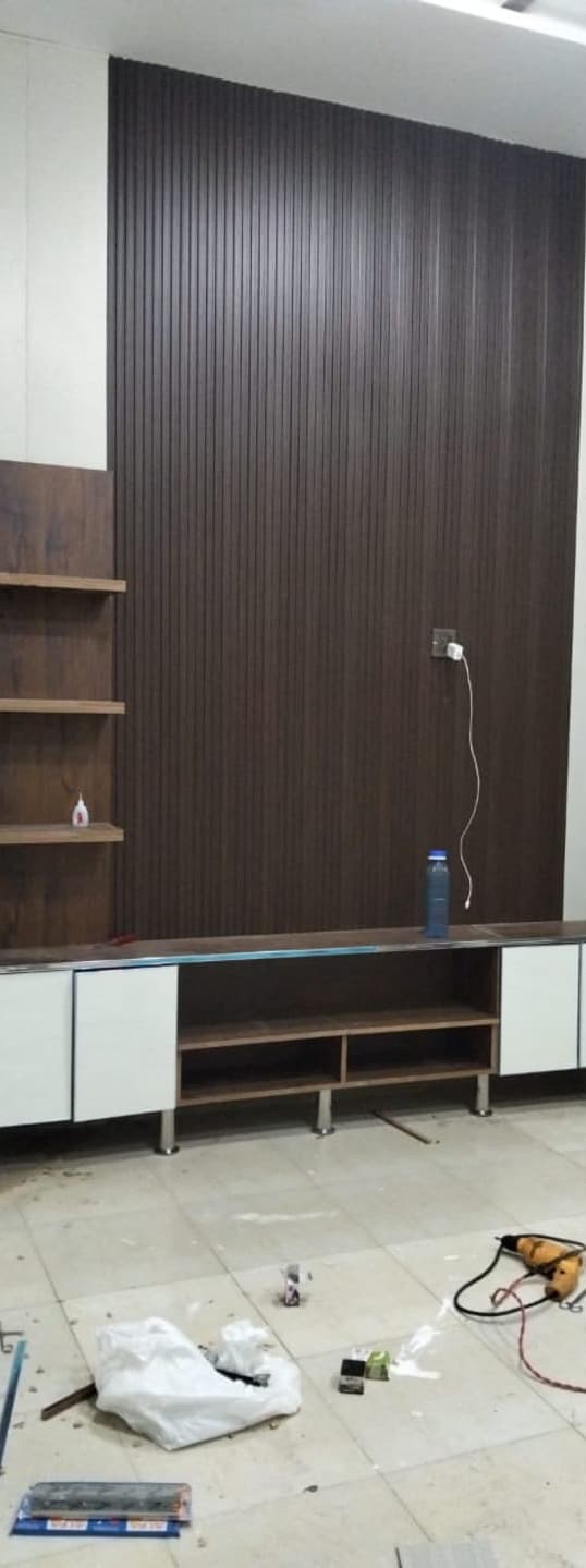 A full-height dark fluted panel wall with a white and wood TV console, newly fitted