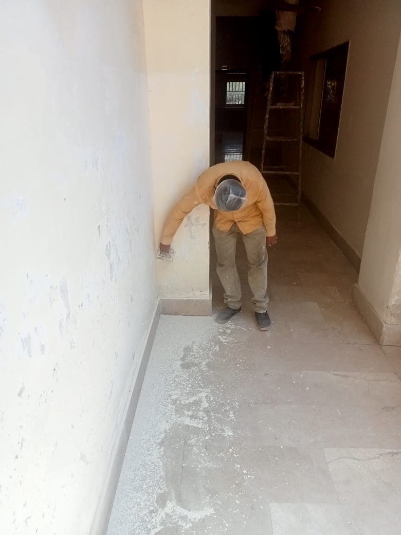 A painter preparing a corridor wall near the floor