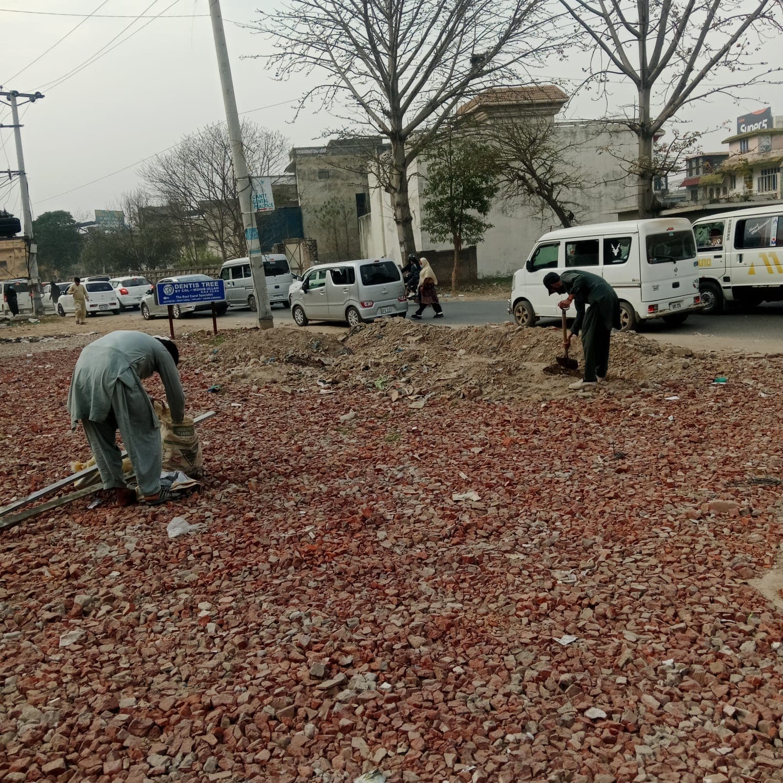 A worker spreading broken brick across the levelled ground