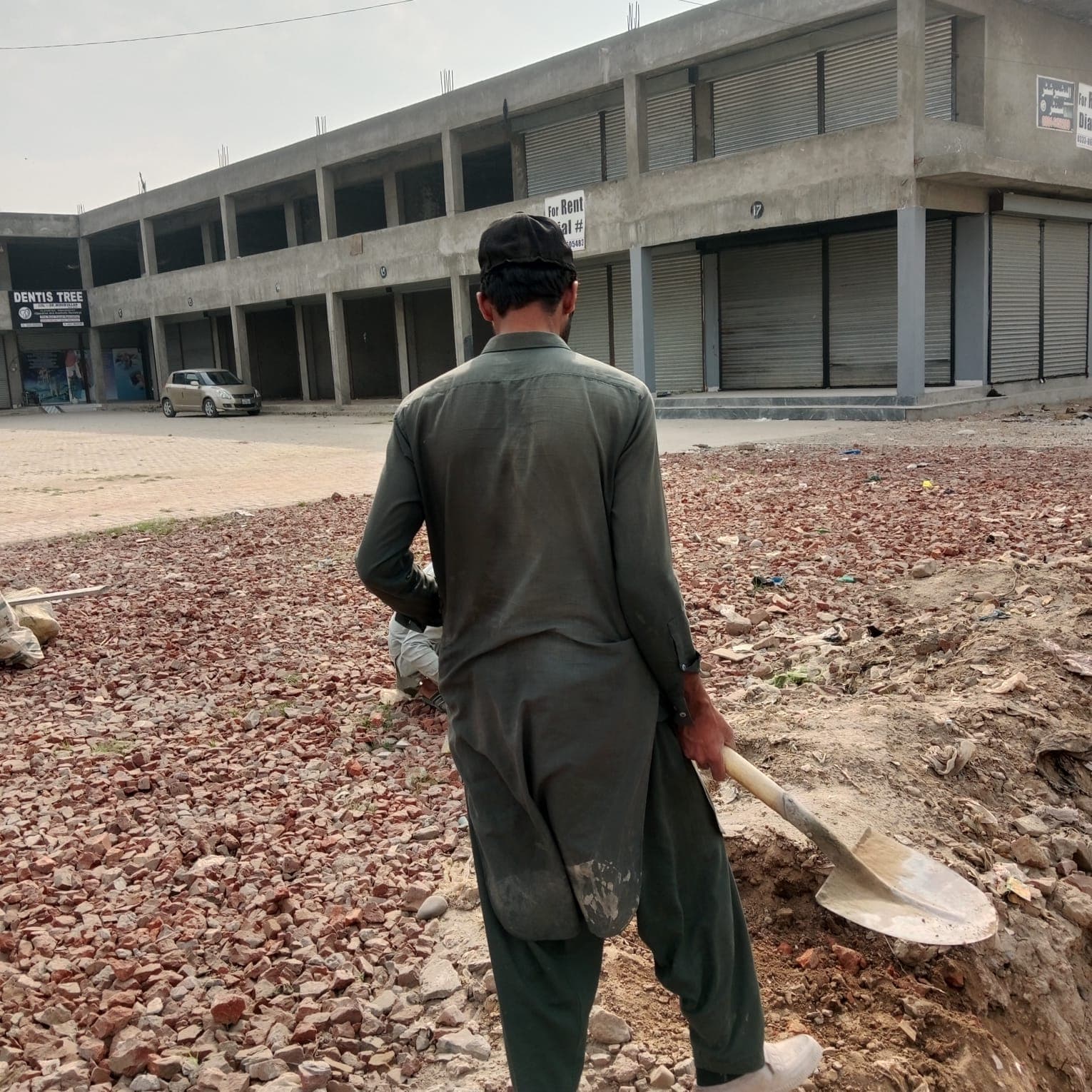 A worker with a shovel spreading the brick base in front of the shops