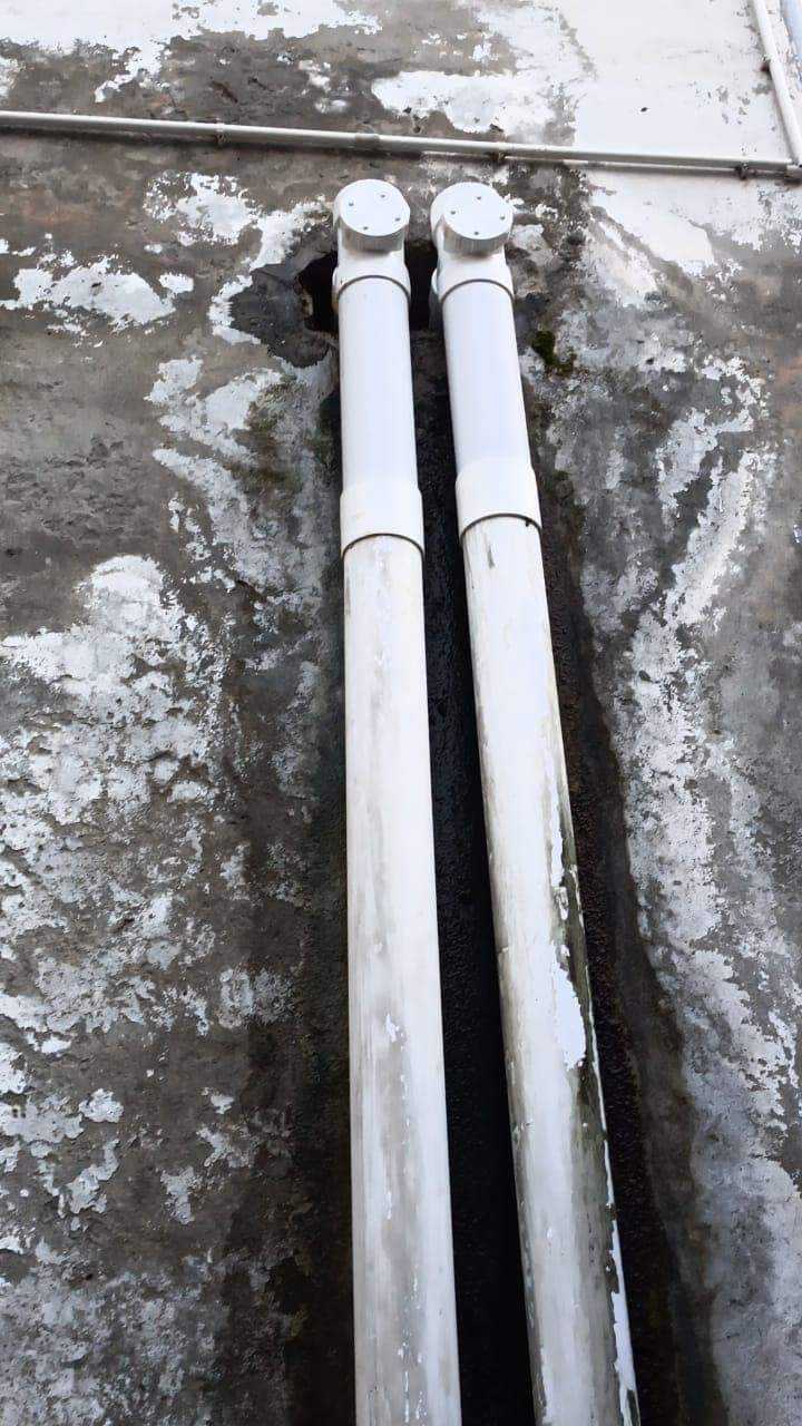 Two new PVC pipes laid in a channel cut through a concrete floor