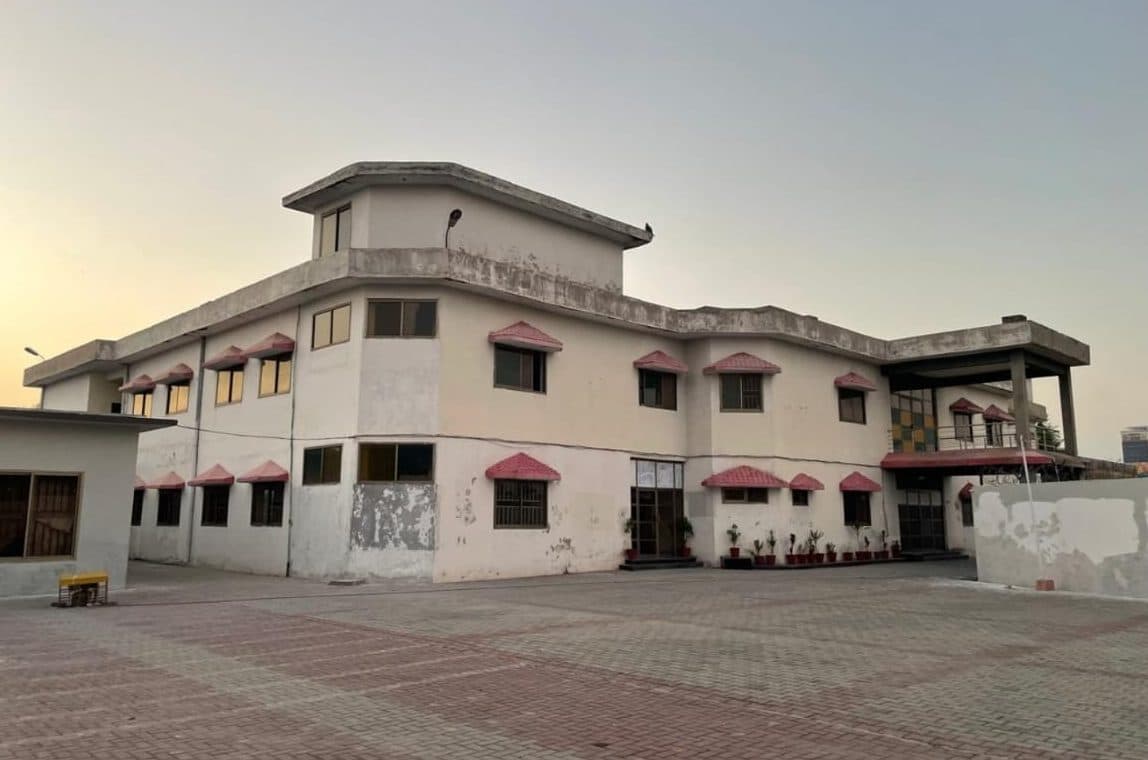 Building with stained, peeling cream walls and red window canopies