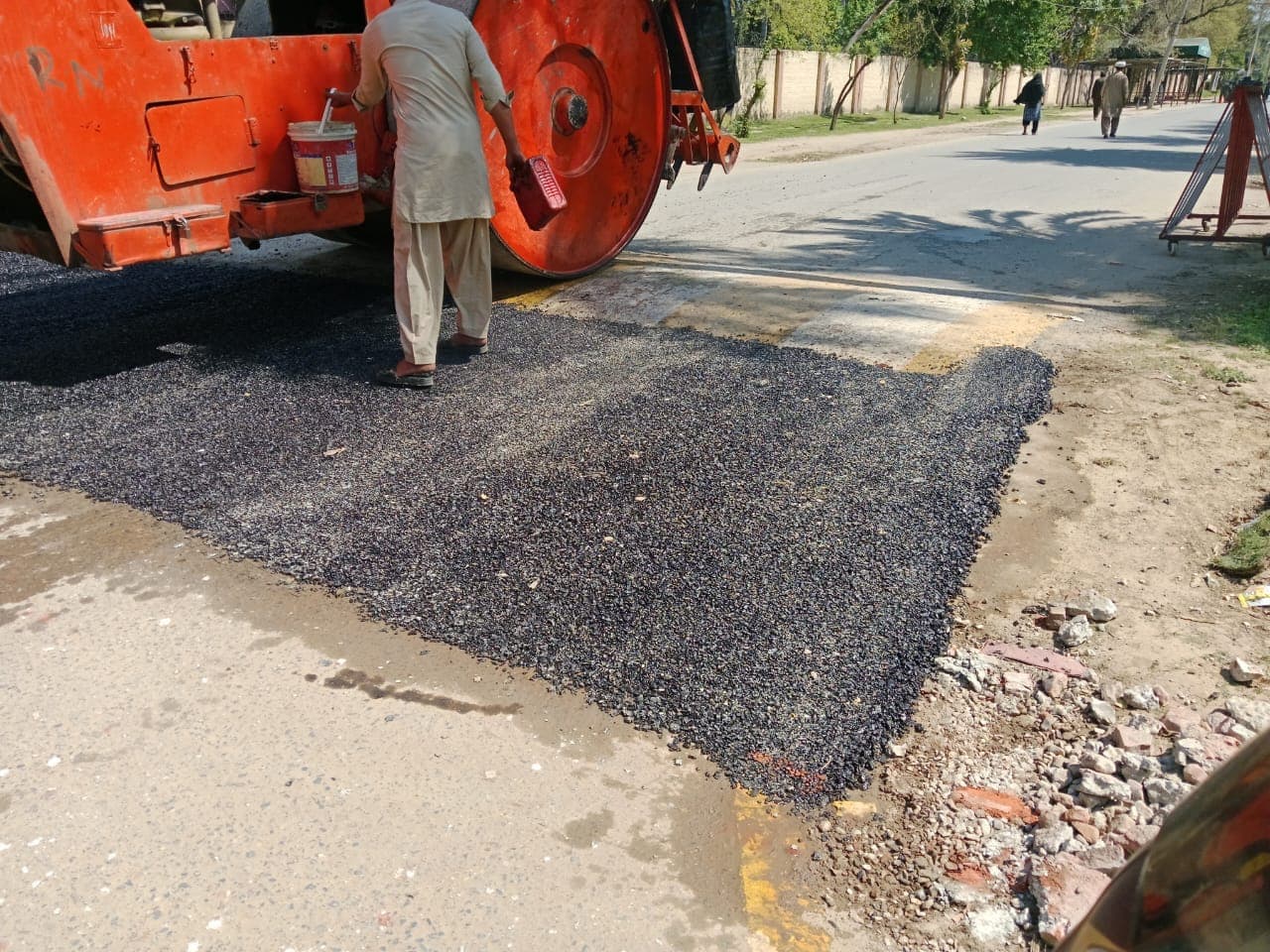 A road roller beside a freshly filled patch, ready to compact it