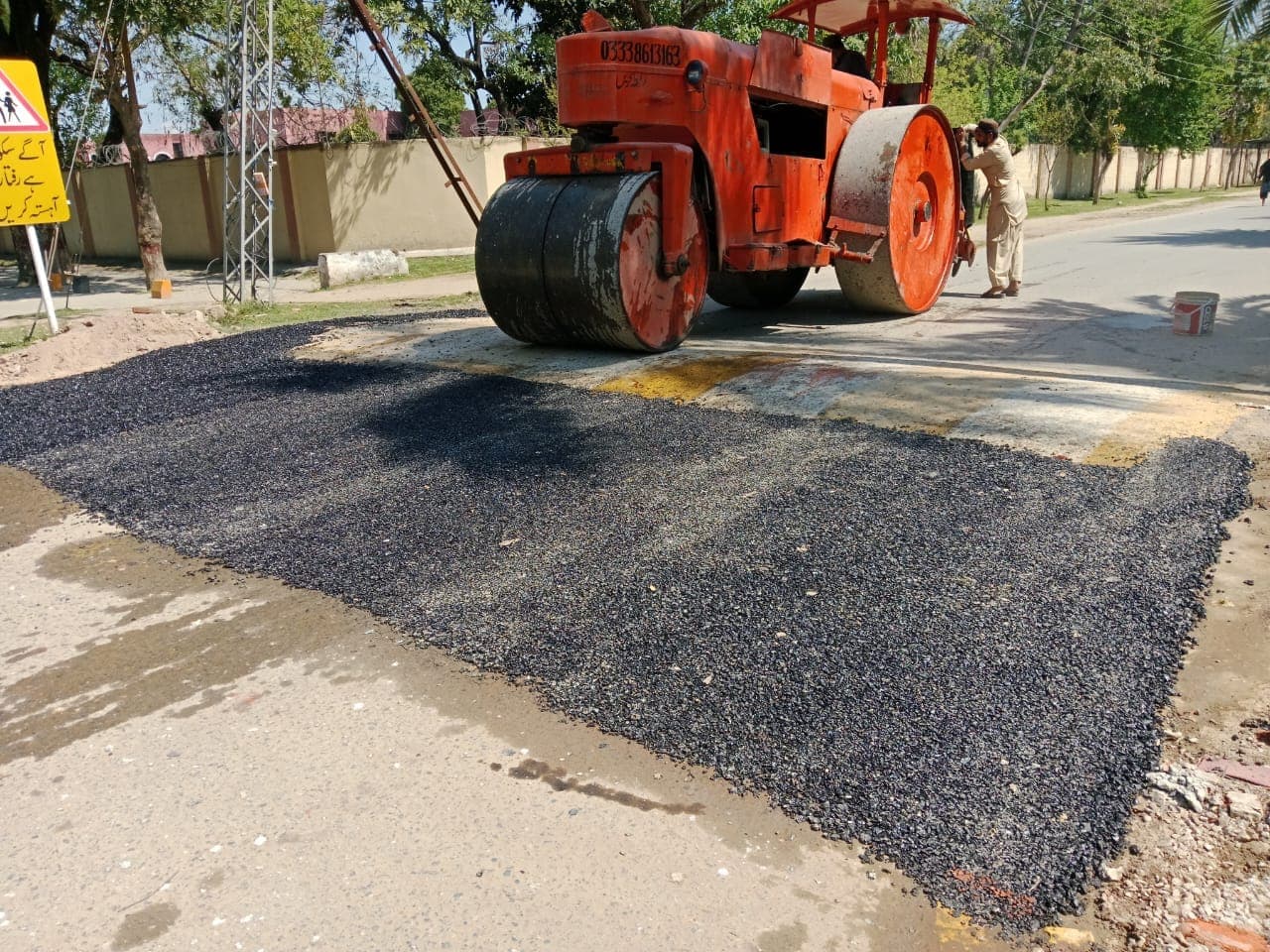 A road roller standing on a compacted patch at a junction