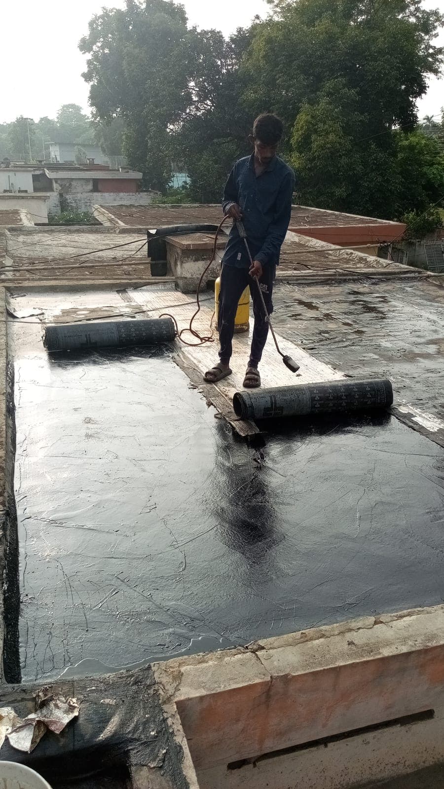A worker torching membrane rolls down onto the primed roof
