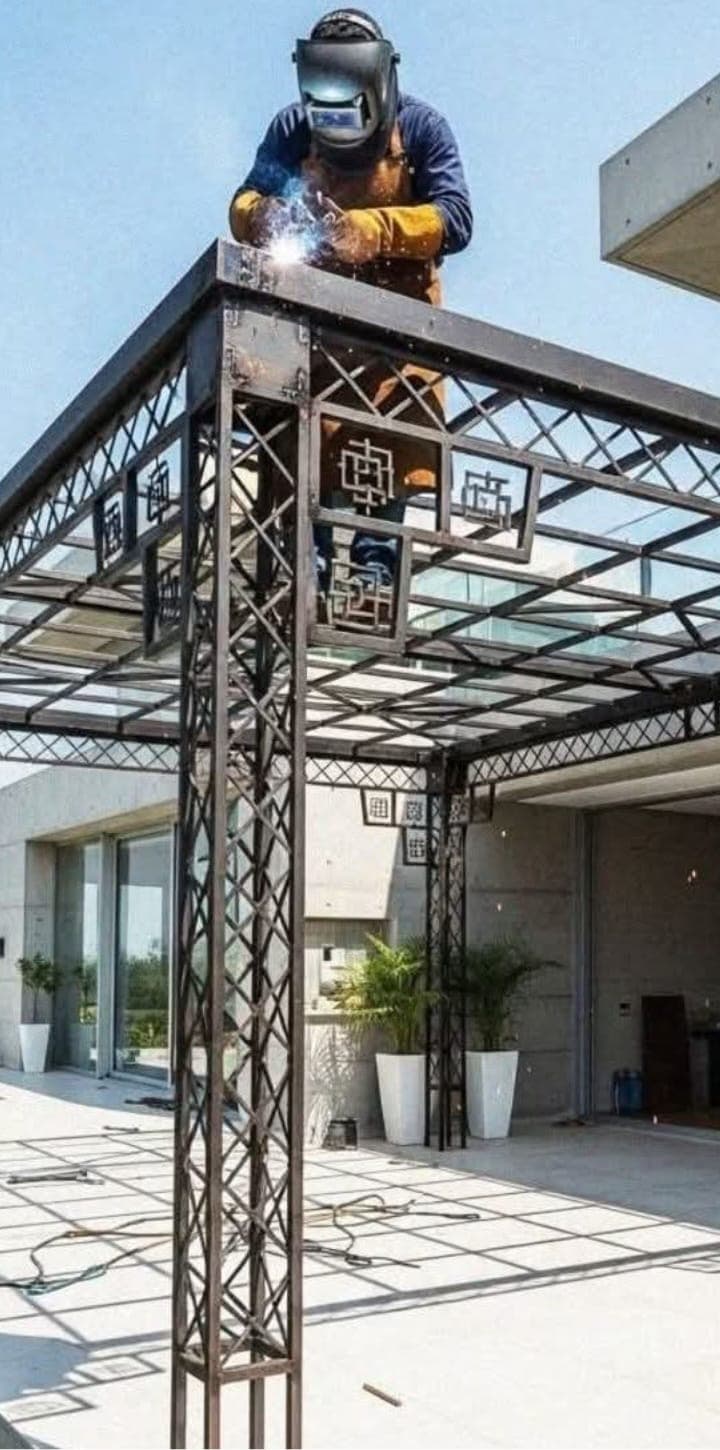 A welder in a mask joining the top of a decorative steel pergola over a terrace