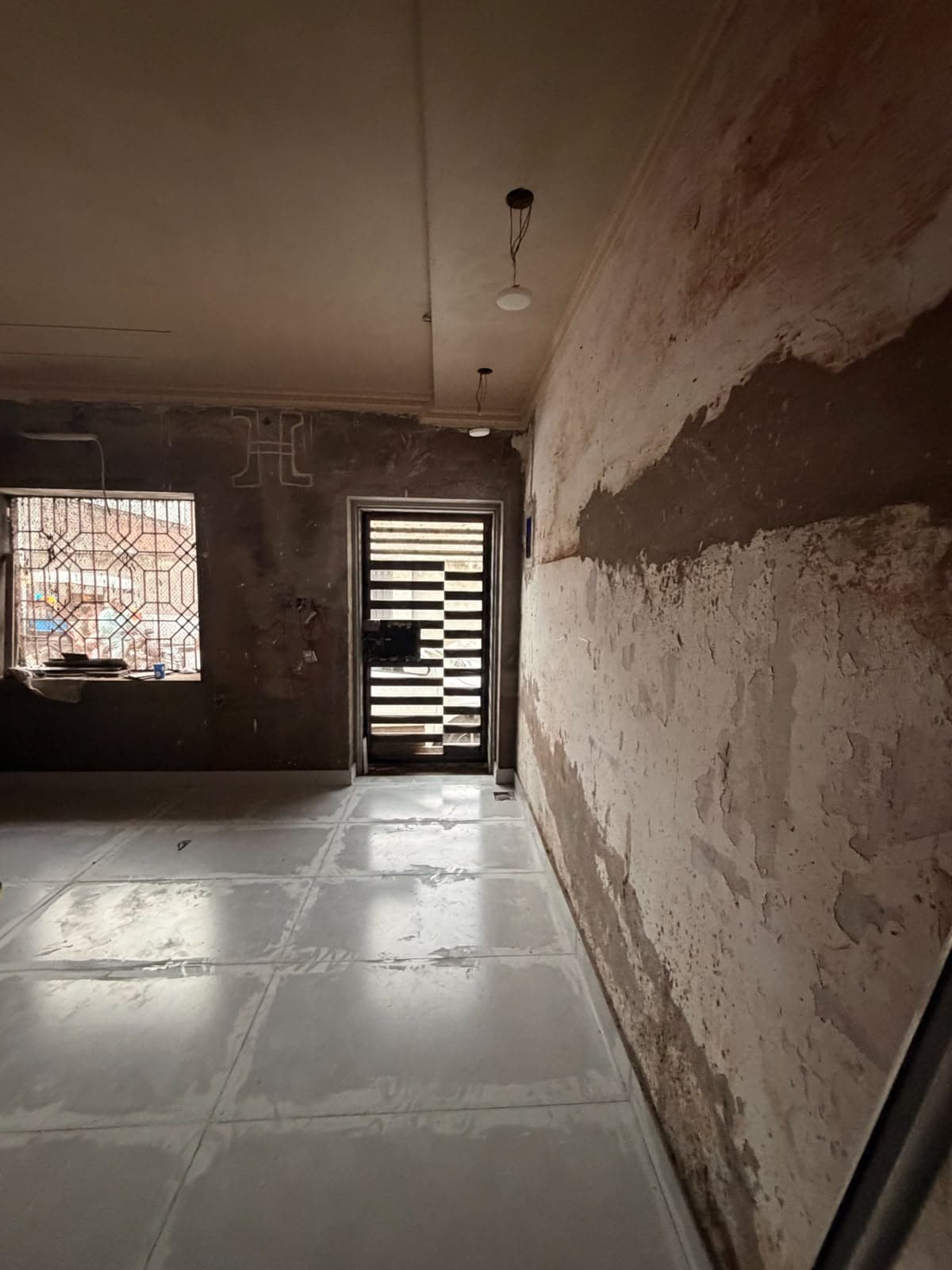 A long room with new glossy floor tiles laid, walls still being plastered