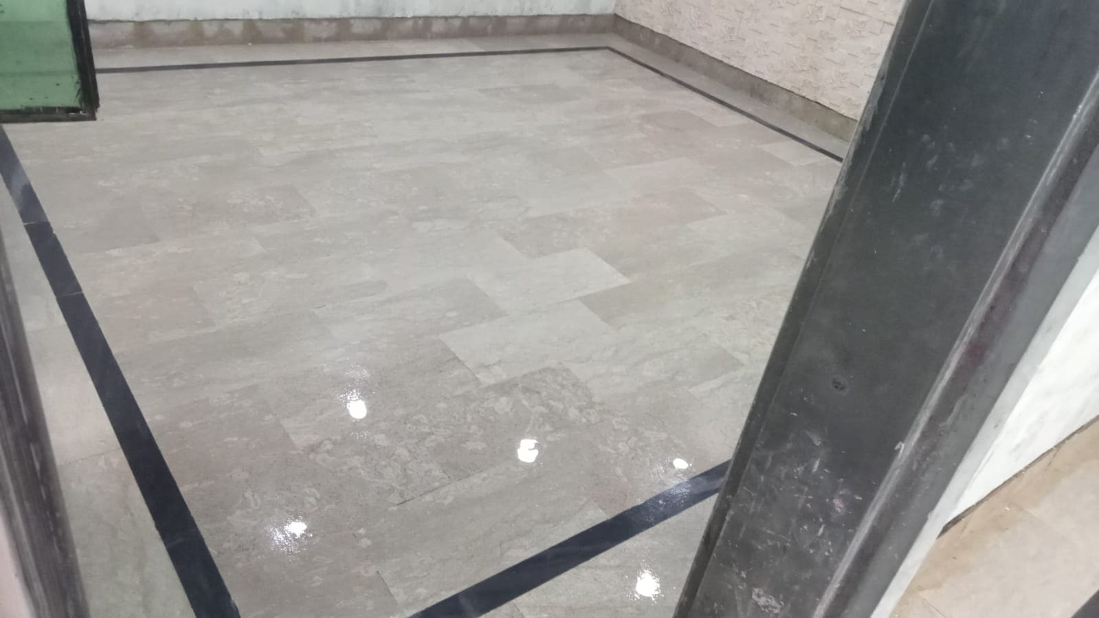 A polished marble floor with a dark border strip, reflecting the light