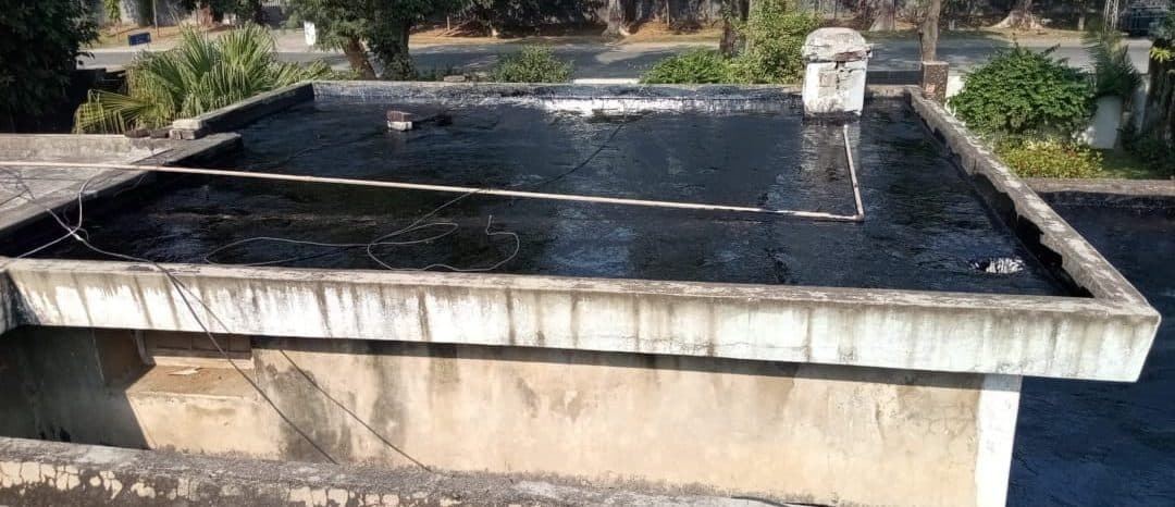 A flat roof fully coated in glossy black bitumen