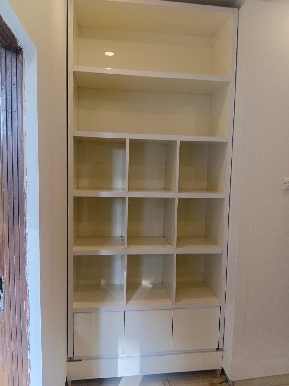 The finished bookcase fitted into a wall niche, with cube shelves and drawers