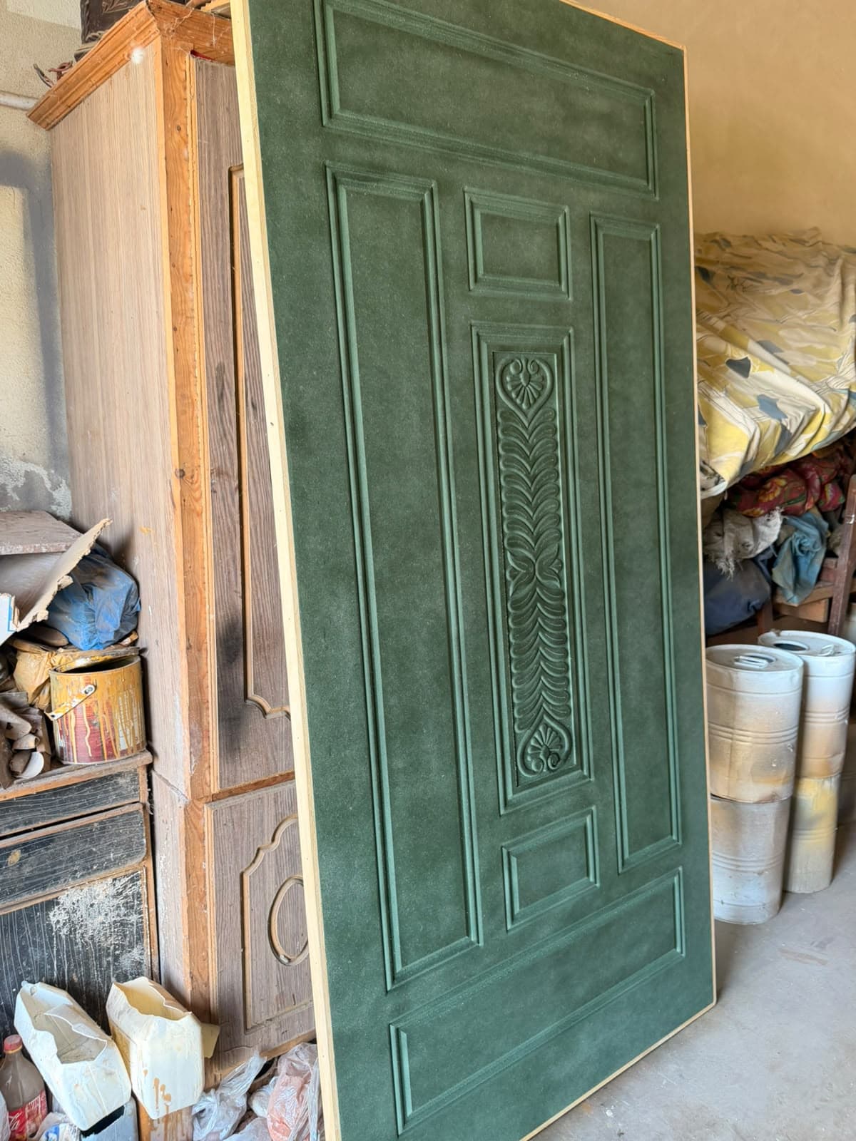 Close-up of a carved green door with raised panels and a centre motif