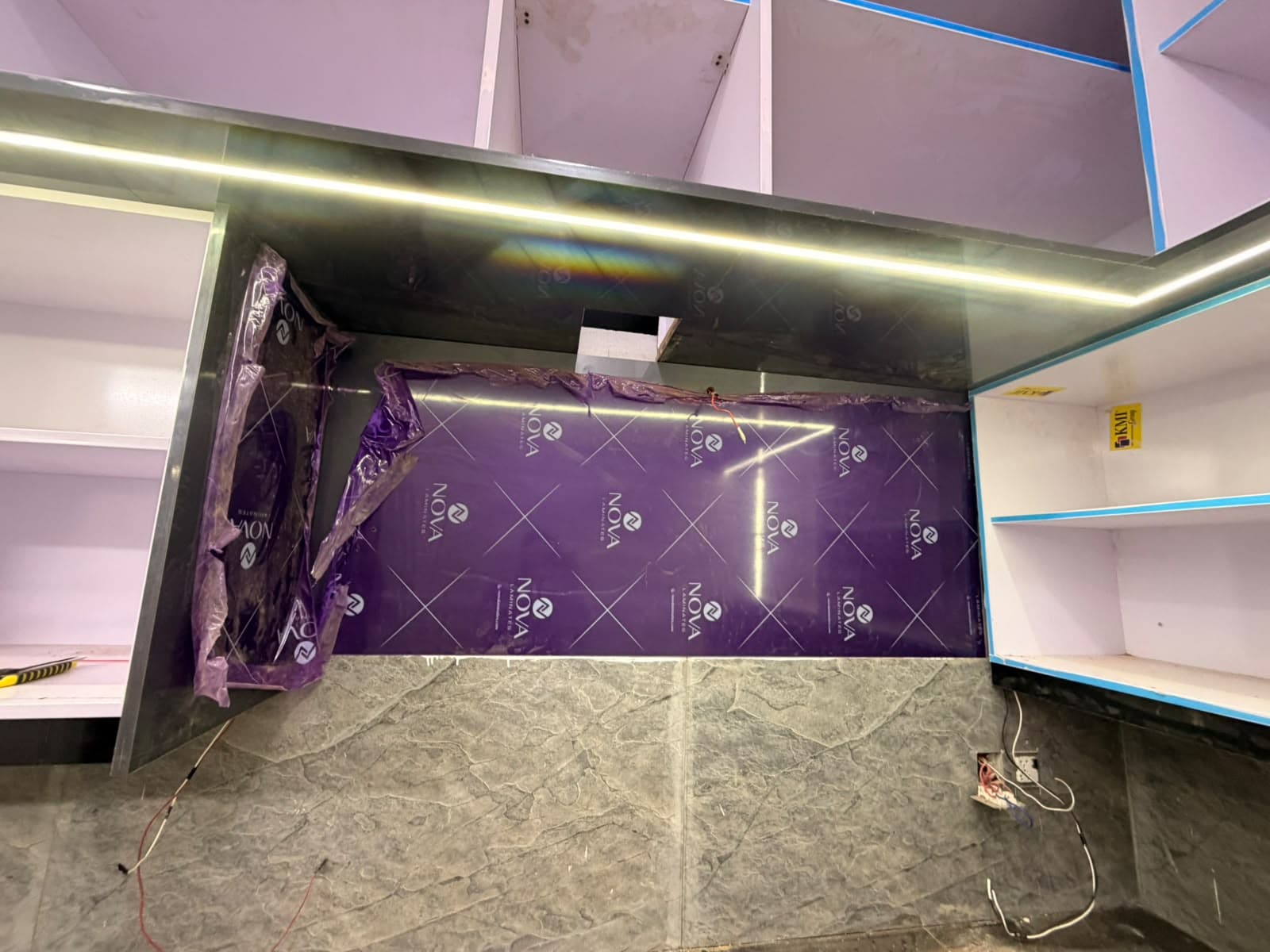 The cooker hood panel and wall units, with the protective film still on the gloss panels